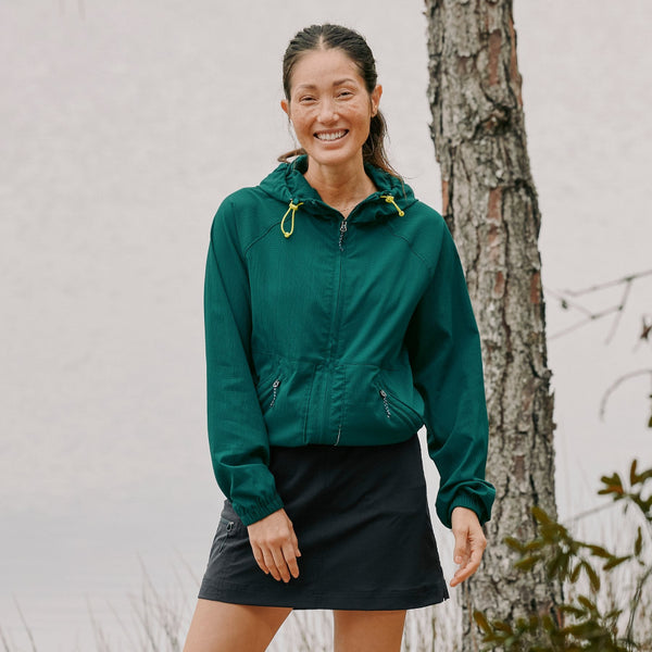 Woman wearing a Green Orvis Women's Open Air Caster Full Zip Sun Hoody standing next to a tree.