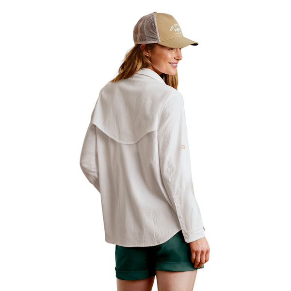 Woman wearing a white Orvis Open Air Caster Relaxed Sun Shirt and green shorts with a beige cap against a white background.