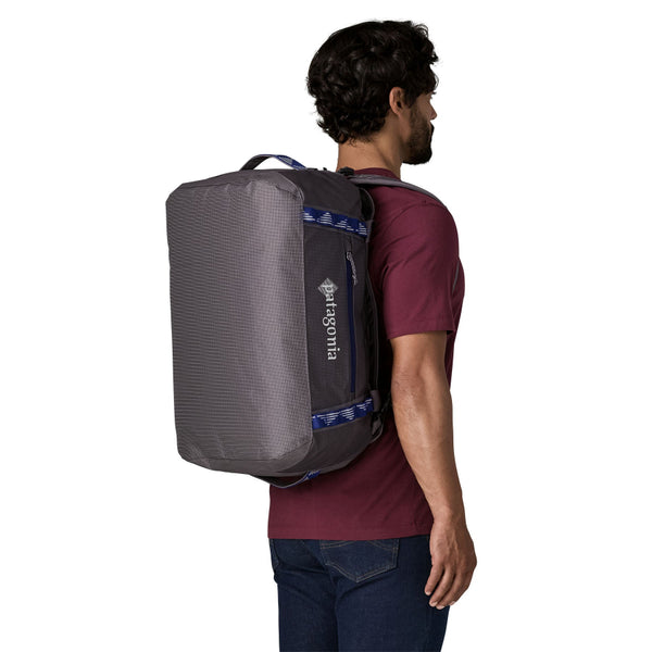 Person wearing the Hut Tripper: May Grey 40-Liter Patagonia Black Hole Duffel Bag shown from the back and side with logo and pocket with blue details visible, on a white background.