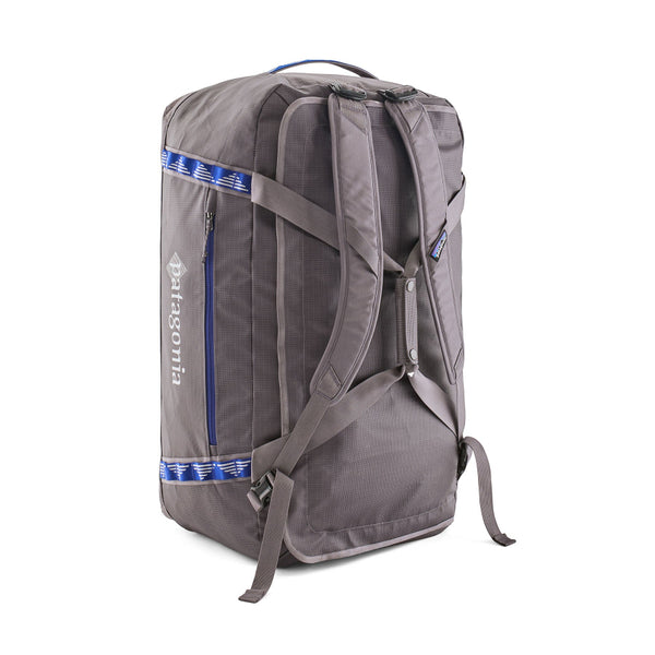 Back pack variation with straps attached of the Hut Tripper: May Grey 70-Liter Patagonia Black Hole Duffel Bag showing side logo and pocket with blue details, on a white background.