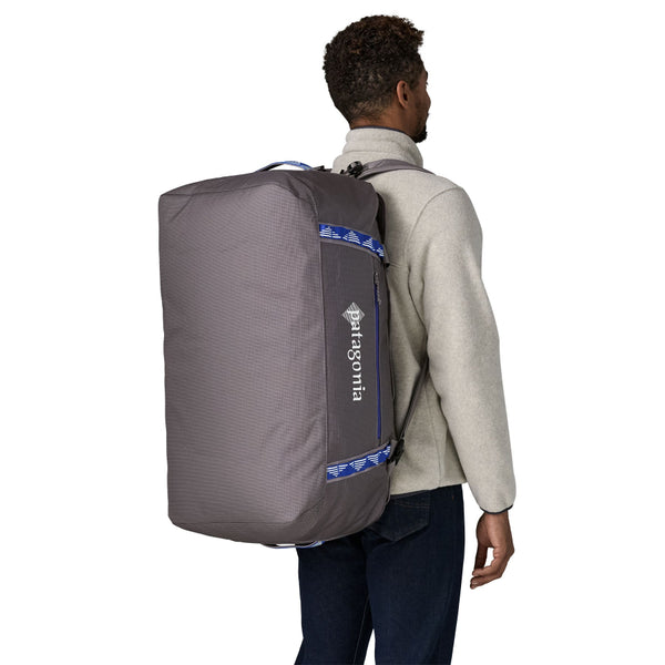 Person wearing the Hut Tripper: May Grey 70-Liter Patagonia Black Hole Duffel Bag shown from the back and side with logo and pocket with blue details visible, on a white background.