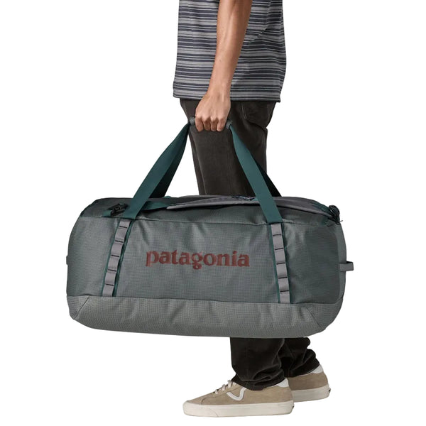 Person holding a noble grey 70-Liter Patagonia Black Hole Duffel Bag against a white background.
