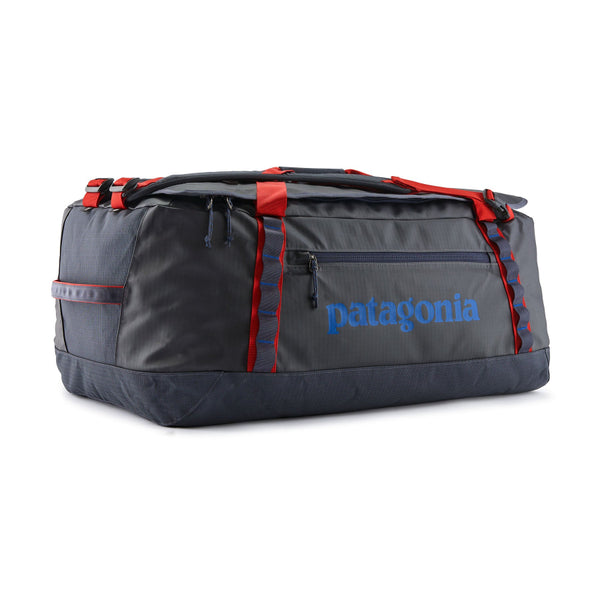 Smolder Blue with Amanita Red 70-Liter Patagonia Black Hole Duffel Bag showing side logo and pocket with red detailing on the straps, on a white background.