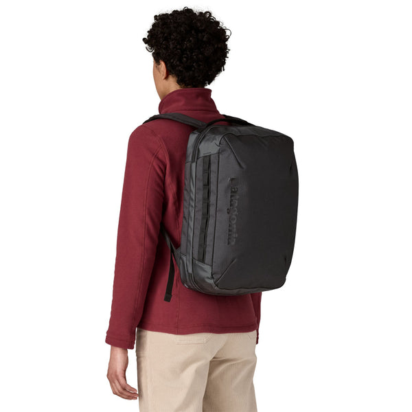 A person wearing a Black Patagonia Black Hole Micro MLC backpack on a white background.