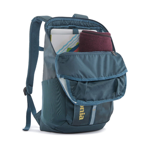 The 25-liter Patagonia Black Hole Backpack in Birch White with blue accents, shown from the front with the main zipper open with clothing and notebooks inside, on a white background.