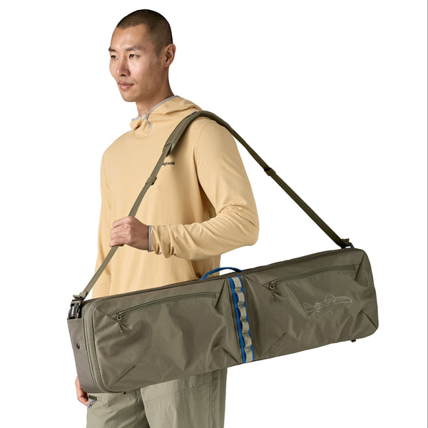 Man carrying a basin green Patagonia Black Hole Fly Fishing Rod Case over his shoulder, on a white background.