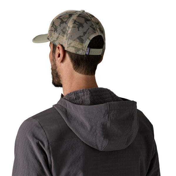 Man wearing a Patagonia jacket and Patagonia Broadcaster Trucker Hat in River Rock Green showing the camo mesh back on a white background.