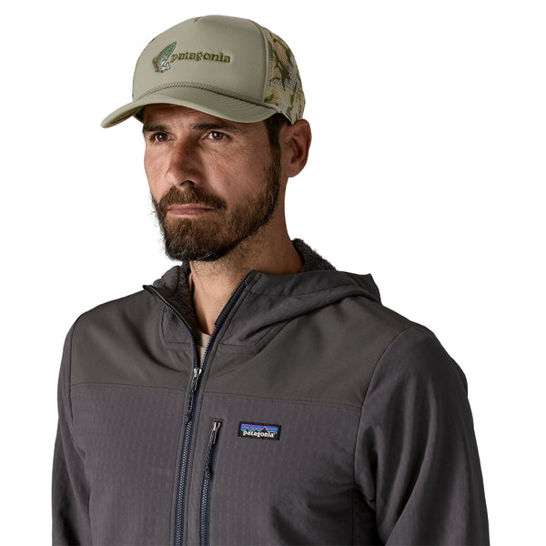 Man wearing a Patagonia jacket and Patagonia Broadcaster Trucker Hat in River Rock Green with fish jump embroidery on the front panel on a white background.