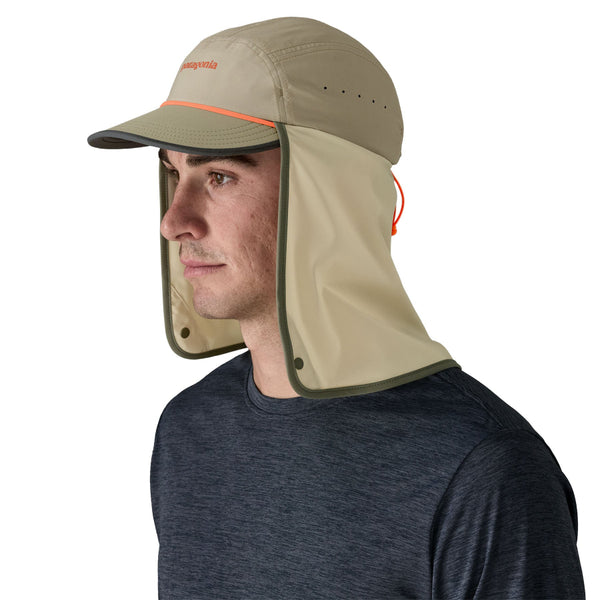 Side view of a person wearing  adark blue shirt and the river rock green Patagonia Caped Merganzer Hat with the full neck coverage panel loose, against a white background.