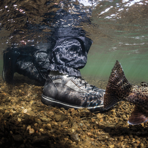 Underwater view of a person wearing Patagonia Foot Tractor Wading boots standing in a river with a fish nearby.