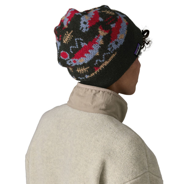 Person wearing a grey Patagonia Fun Hog Knit beanie with colorful salmon designs, and a light tan jacket over a white background.