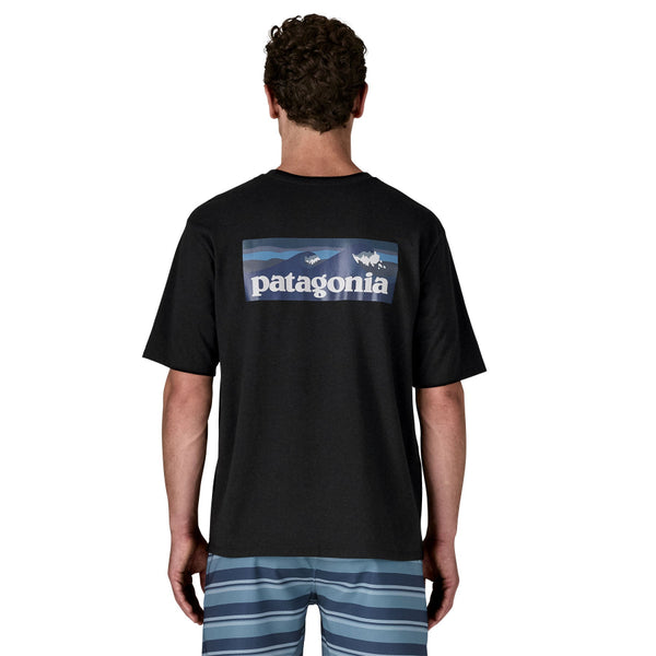 Person wearing a black Patagonia Boardshorts Logo t-shirt with a graphic on the back, standing against a white background.