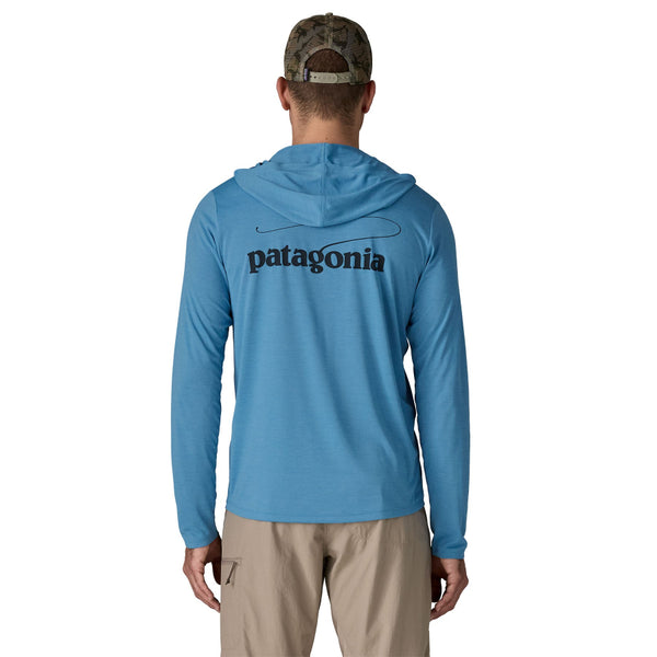 Person wearing khaki pants and the shore blue x-dye Patagonia Men's Capilene Cool Daily Hoody with a Casting Logo design on the back against a white background.