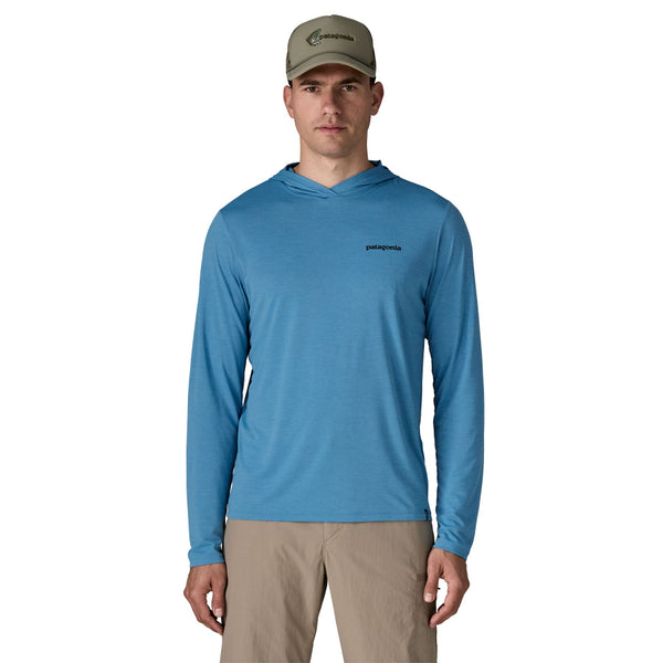 Person wearing khaki pants and the shore blue x-dye Patagonia Men's Capilene Cool Daily Hoody Casting Logo facing forward against a white background.