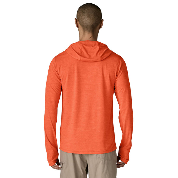 Person wearing a coal orange x-dye Patagonia Men's Capilene Cool Sun Hoody and khaki pants against a white background.