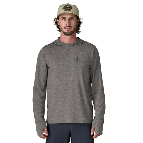 Person wearing blue pants and a noble grey x-dye Patagonia Men's Capilene Cool Sun Hoody, with front zipper pocket on left chest, against a white background.