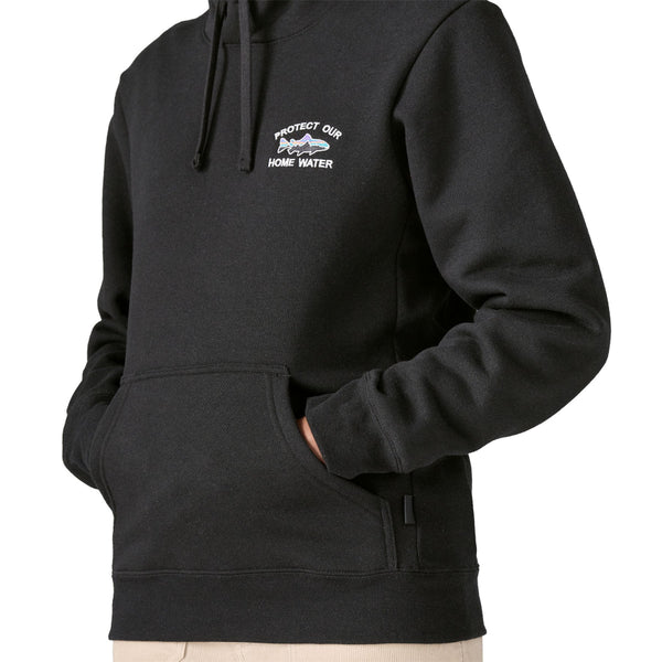 Person wearing the black Patagonia Men's Home Water Trout Uprisal Hoody showing the front pocket detail against a white background.