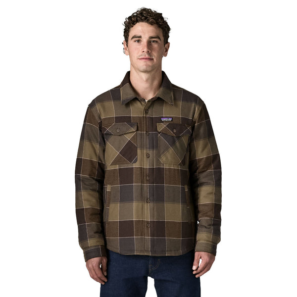 A person wearing jeans and the Patagonia Men's Insulated Fjord Flannel Shirt with a button top pockets on the chest, in basin green snow owl plaid, shown against a white background.