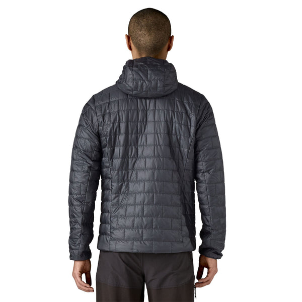 Person wearing black pants and a smolder blue Patagonia Men's Nano Puff Insulated Hoody, with brick quilting and a full coverage hood, shown from the back against a white background.