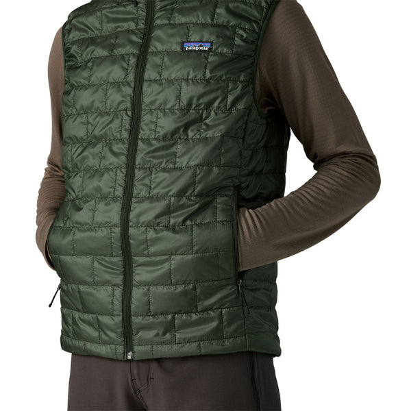 Person wearing the old growth green Patagonia Men's Nano Puff quilted vest showing pocket details on a white background.
