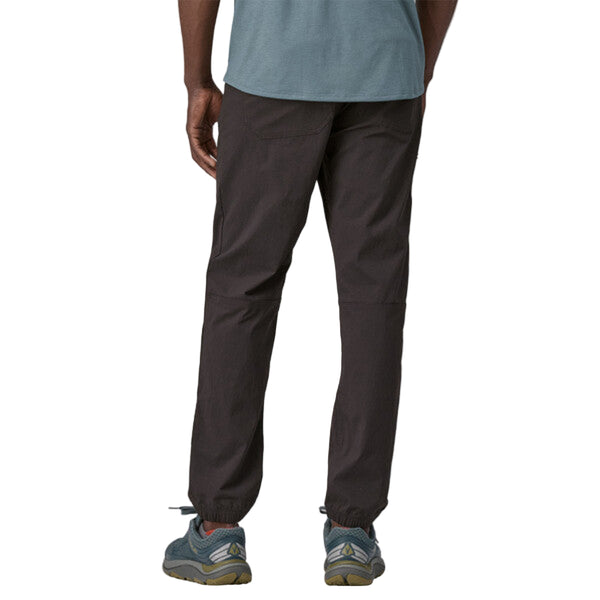 Person wearing Patagonia Men's Quandary Joggers in black, featuring multiple pockets and a drawcord waistband on a white background.