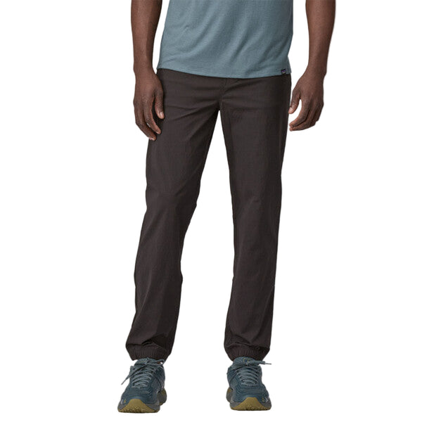 Person wearing Patagonia Men's Quandary Joggers in black, featuring multiple pockets and a drawcord waistband on a white background.