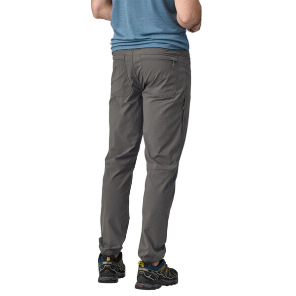 Person wearing Patagonia Men's Quandary Joggers in grey, featuring multiple pockets and a drawcord waistband on a white background.