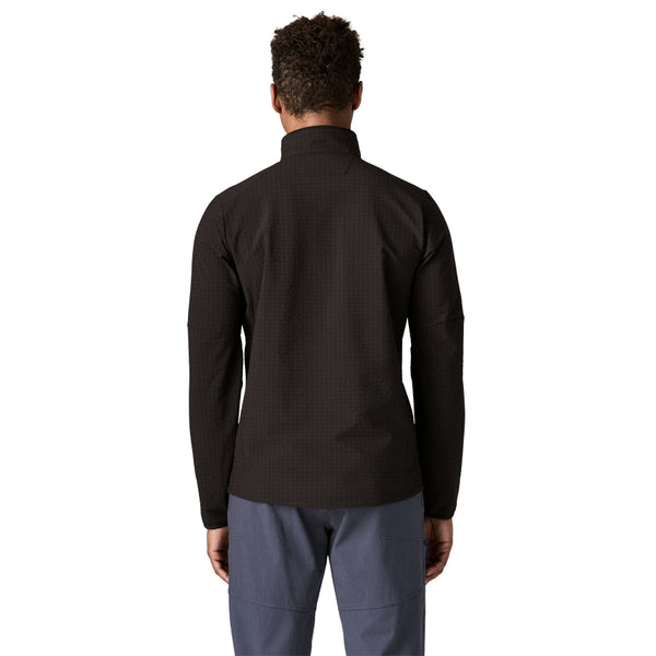 Person wearing a black Patagonia Men's R1 TechFace Jacket and grey pants on a white background.