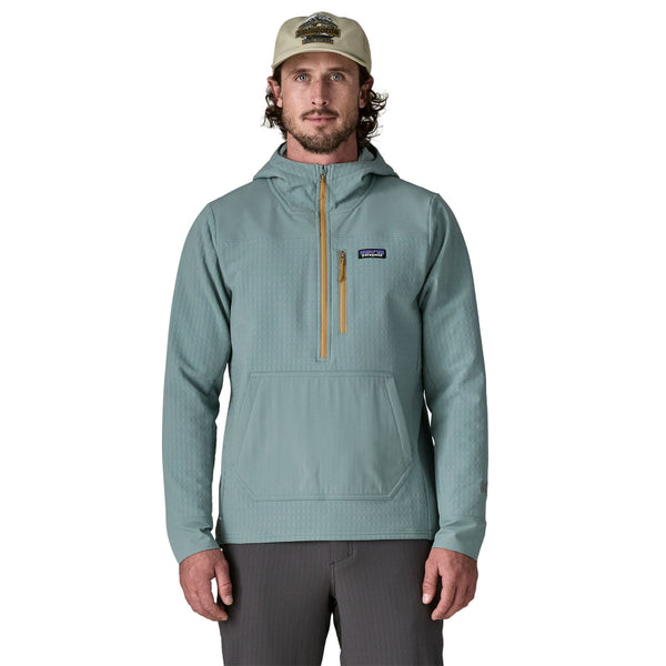 Man wearing grey pants and the blue sage hooded Patagonia Men's R2 Techface Pullover with a zipper front pocket on a white background.