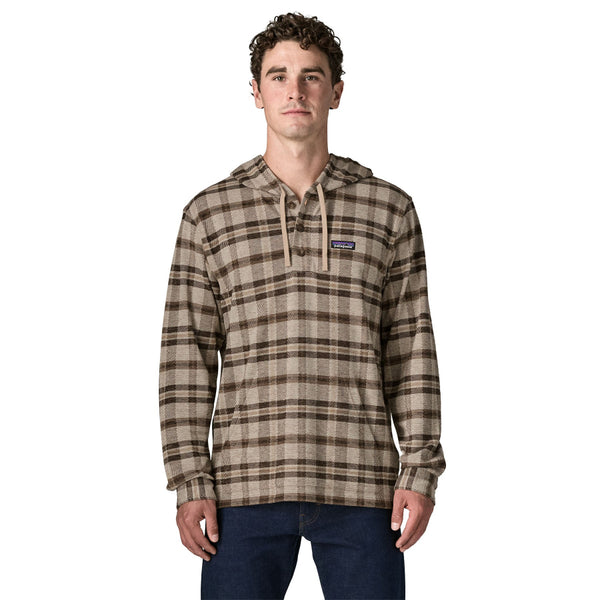 Person wearing blue jeans and a Patagonia Men's Stretch Fjord Flannel hooded pullover shirt brown and beige plaid, against a white background.