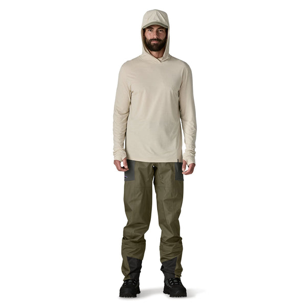 Person wearing a beige sun hoody and set of Patagonia Men's Swiftcurrent Pant Waders in basin green, on a white background.