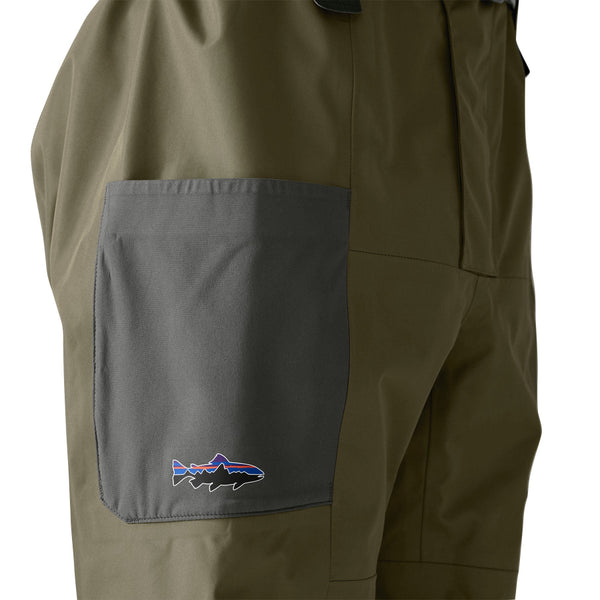 Person wearing a set of Patagonia Men's Swiftcurrent Pant Waders in basin green, close up on the side pocket, on a white background.