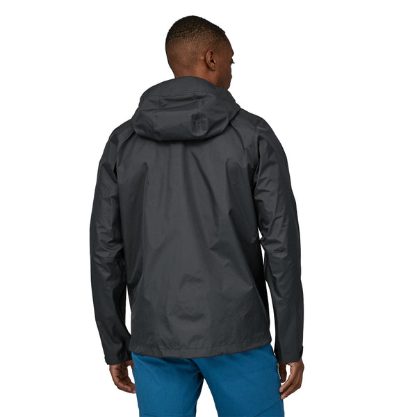 Person wearing a Patagonia Men's Torrentshell 3L Rain Jacket in black and blue pants on a white background.