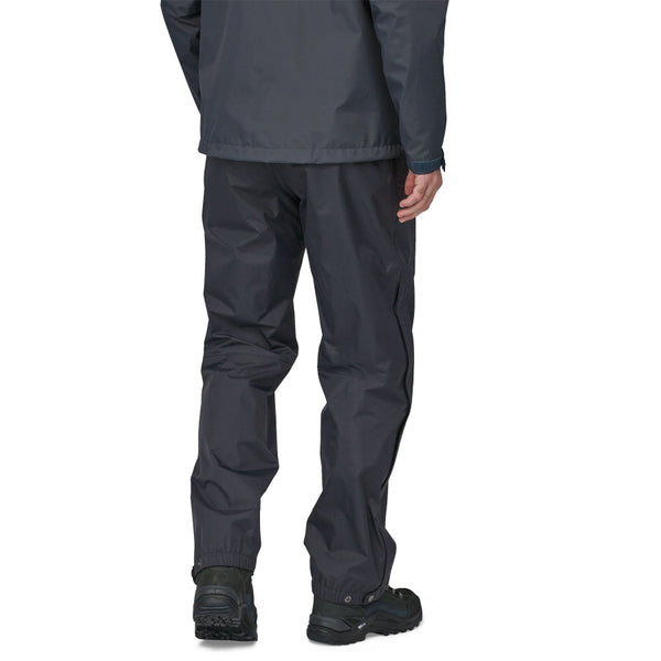 Person wearing black Patagonia Men's Torrentshell Rain Pants and Jacket on a white background.