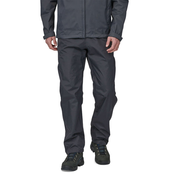 Person wearing black Patagonia Men's Torrentshell Rain Pants and Jacket on a white background.