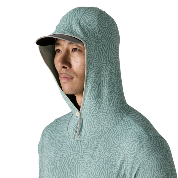 Person wearing khakis and the sea run - sage blue color Patagonia Men's Tropic Comfort Natural Sun Hoody on a white background.