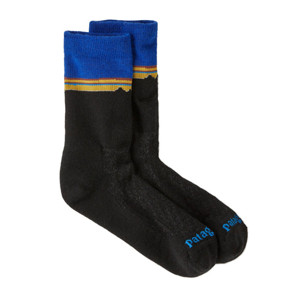 Black Patagonia Merino Crew socks with blue top and yellow fitz roy stripe on a white background.