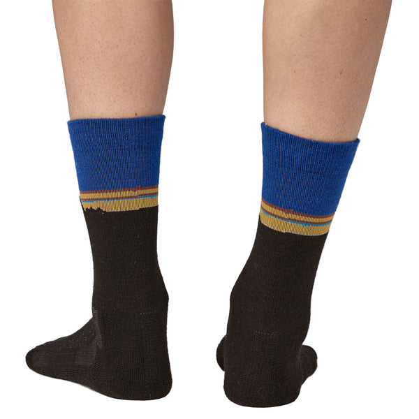 Black Patagonia Merino Crew socks with blue top and yellow fitz roy stripe on a white background.