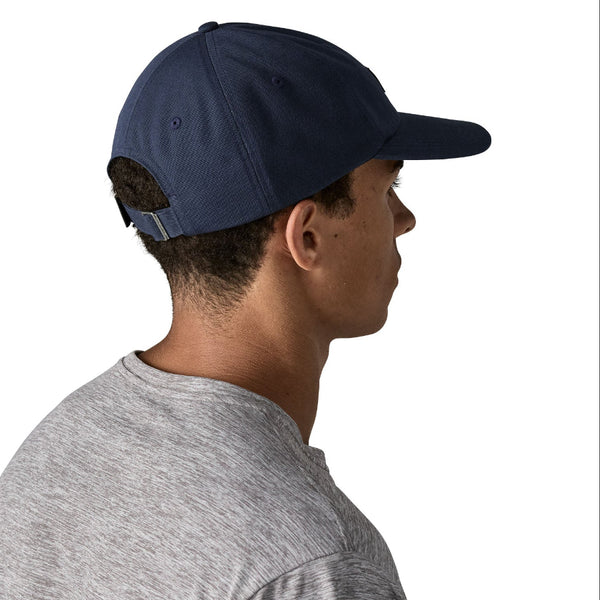Person wearing a grey t-shirt and a new navy color full cloth Patagonia P-6 Label Trad Cap, showing the back closure strap, on a white background.