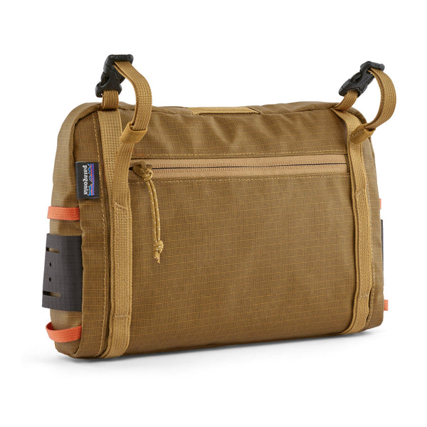 A Patagonia Stealth Switch Pack 3L in bobcat brown color designed for carrying fishing equipment and showing back side on a white 