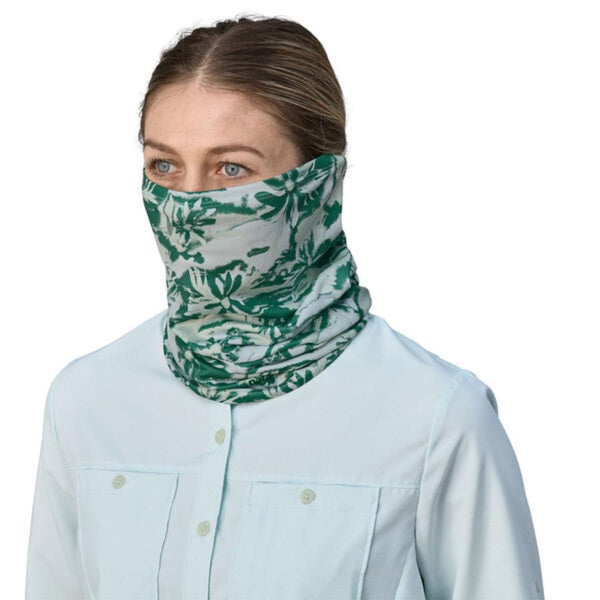 A person wearing a wispy green cliffs and waves patterned Patagonia UPF Sun Mask on a white background.