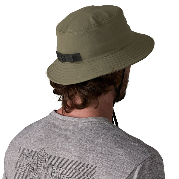Person wearing a grey t-shirt and the basin green color Patagonia Surf Brimmer Bucket Hat, on a white background.