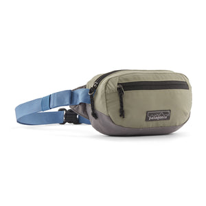 A Patagonia Terravia Mini Hip Pack in blue and grey colors, featuring multiple zippers and a adjustable waist belt, on a white background.