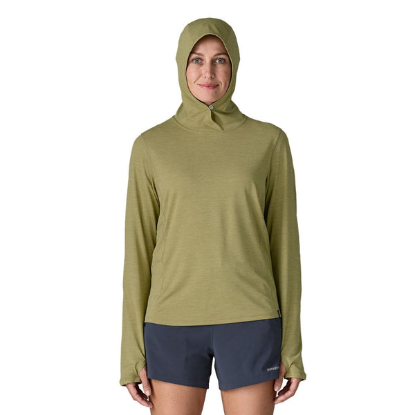 Person wearing a gumtree green x-dye Patagonia Women's Capilene Cool Sun Hoody and black shorts against a white background.