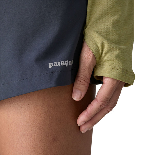 Person wearing a gumtree green x-dye Patagonia Women's Capilene Cool Sun Hoody showing the sleeve thumb loop details, against a white background.