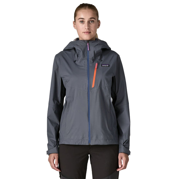 Person wearing black pants and a smolder blue Patagonia Women's Granite Crest Rain Jacket with a blue front zipper and orange pocket zip, on a white background.