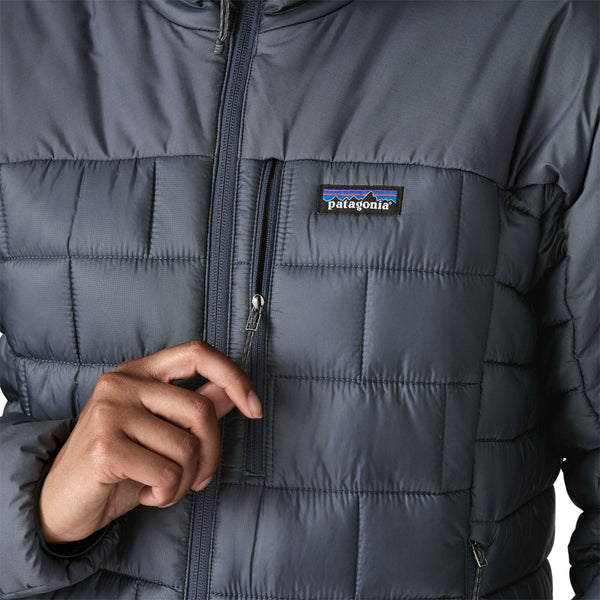Person wearing the new for 2025 Patagonia Women's Hi-Loft Nano Puff Hoody in smolder blue showing front pocket details on a white background.