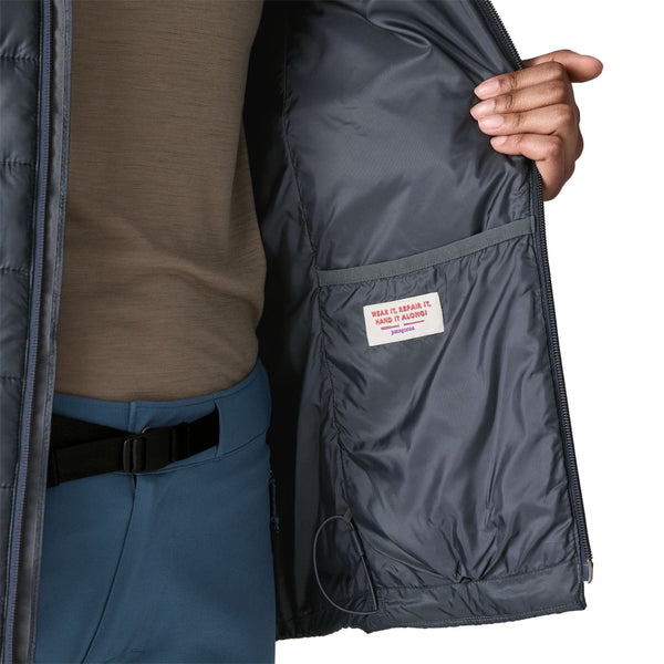 Person wearing the new for 2025 Patagonia Women's Hi-Loft Nano Puff Hoody in smolder blue showing interior pocket details on a white background.
