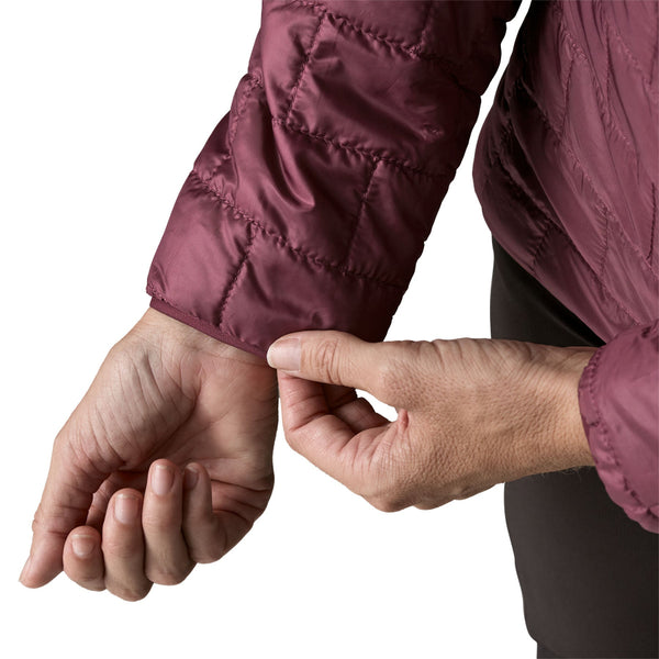 A person wearing the berry fig color Patagonia Women's Nano Puff Hoody showing the cuff details, on a white background.