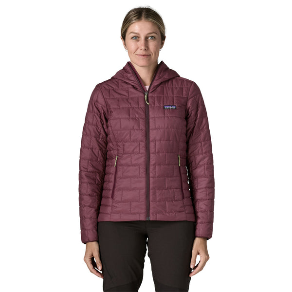 A person wearing black pants and the berry fig color Patagonia Women's Nano Puff Hoody featuring quilting and full front zipper, on a white background.